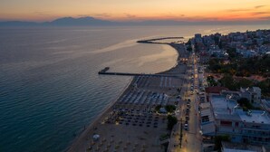 A coastal cityscape with a beach, a pier, and a row of buildings along the waterfront. - Light Blue Luxury Rooms (Nea Propontida)