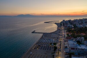 Un paisaje urbano costero con una playa, un muelle y una hilera de edificios a lo largo de la costa.