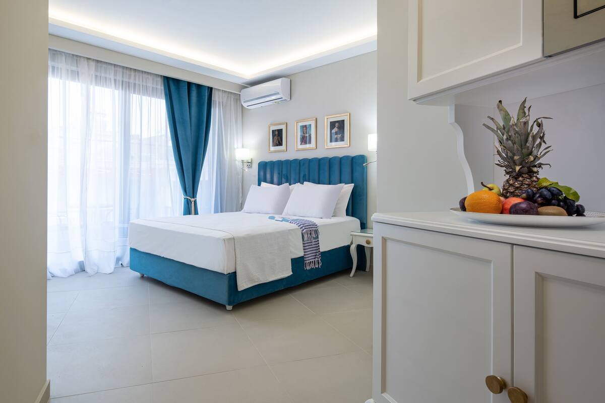 A hotel room with a bed, a nightstand, a fruit bowl, and a cabinet.