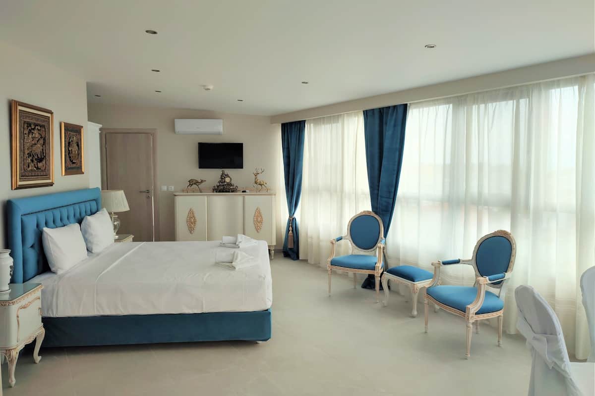 A hotel room with a large bed, a desk, two chairs, and a television on the wall.