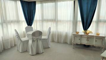 Ein Zimmer mit Tisch, Stühlen, einem weißen Schrank und blauen Vorhängen.