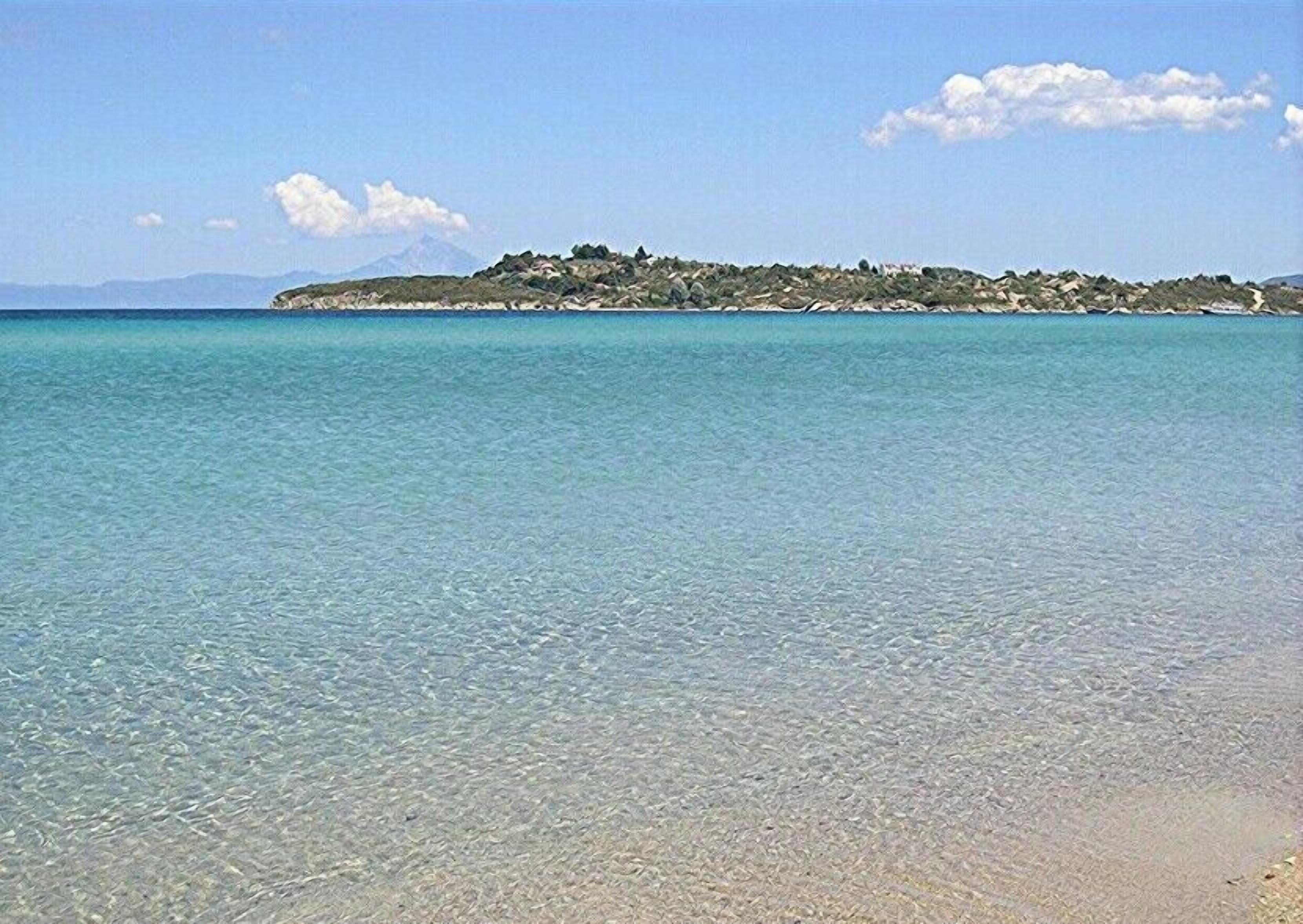 Una playa despejada con una isla rocosa al fondo.