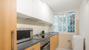 A modern kitchen with a microwave, oven, sink, and a washing machine.