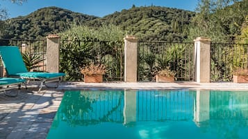 Una piscina al aire libre, sombrillas, sillones reclinables de piscina