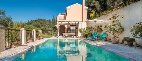 Una piscina al aire libre, sombrillas, sillones reclinables de piscina