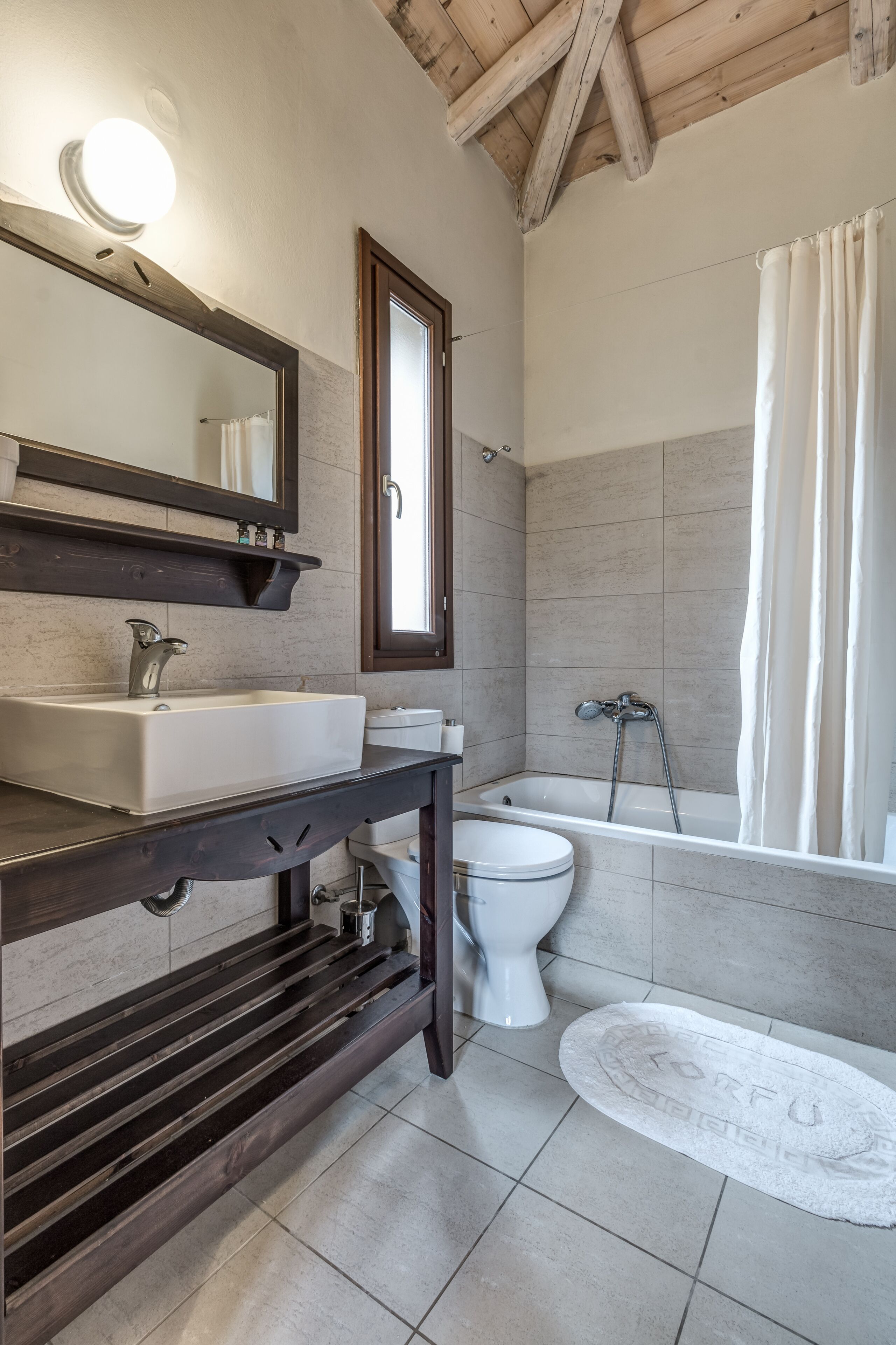A bathroom with a sink, mirror, and bathtub.