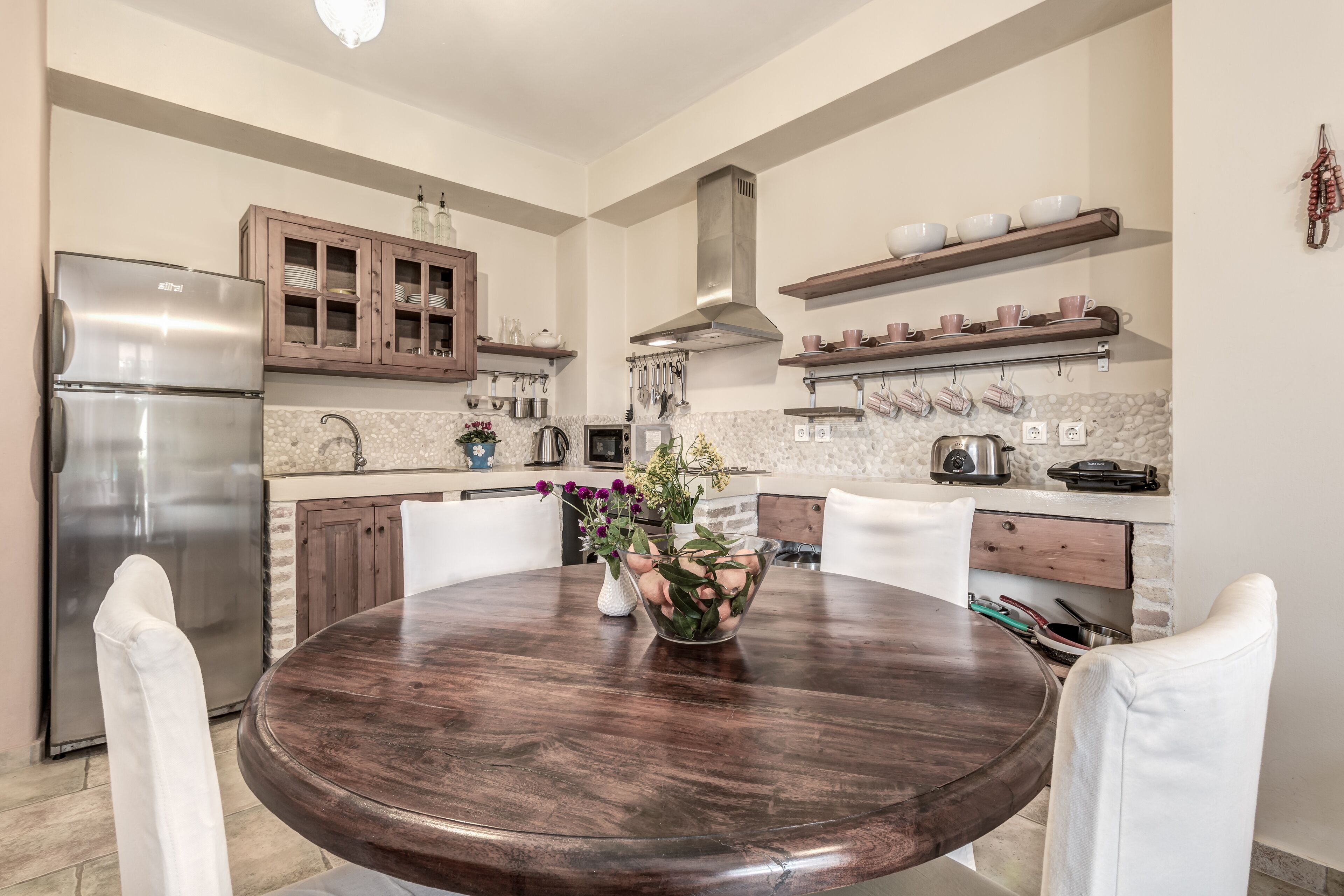Een moderne keuken met een centraal eiland, roestvrijstalen apparatuur, houten kastjes en decoratieve accessoires.