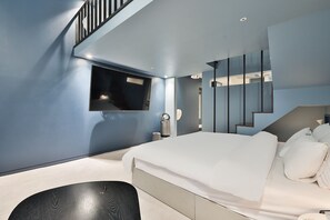 A modern bedroom with a large bed, a built-in TV, a staircase, and a minimalist design.