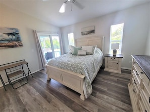 A bedroom with a bed, bedside tables, a dresser, and a window.
