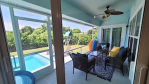 Una veranda coperta con vista su una piscina, mobili da esterno e una ventola a soffitto.
