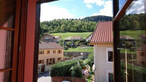 A view from a window overlooking a residential area with houses, a playground, and a forested hill in the background. - Apartment with a view in the center of Bussang (Bussang)