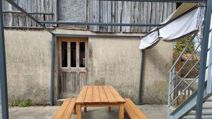 A wooden picnic table with benches in an outdoor area with a concrete floor and a metal staircase. - Apartment with a view in the center of Bussang (Bussang)
