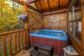 Une terrasse en bois avec un jacuzzi, des bancs en bois et un mur en treillis.