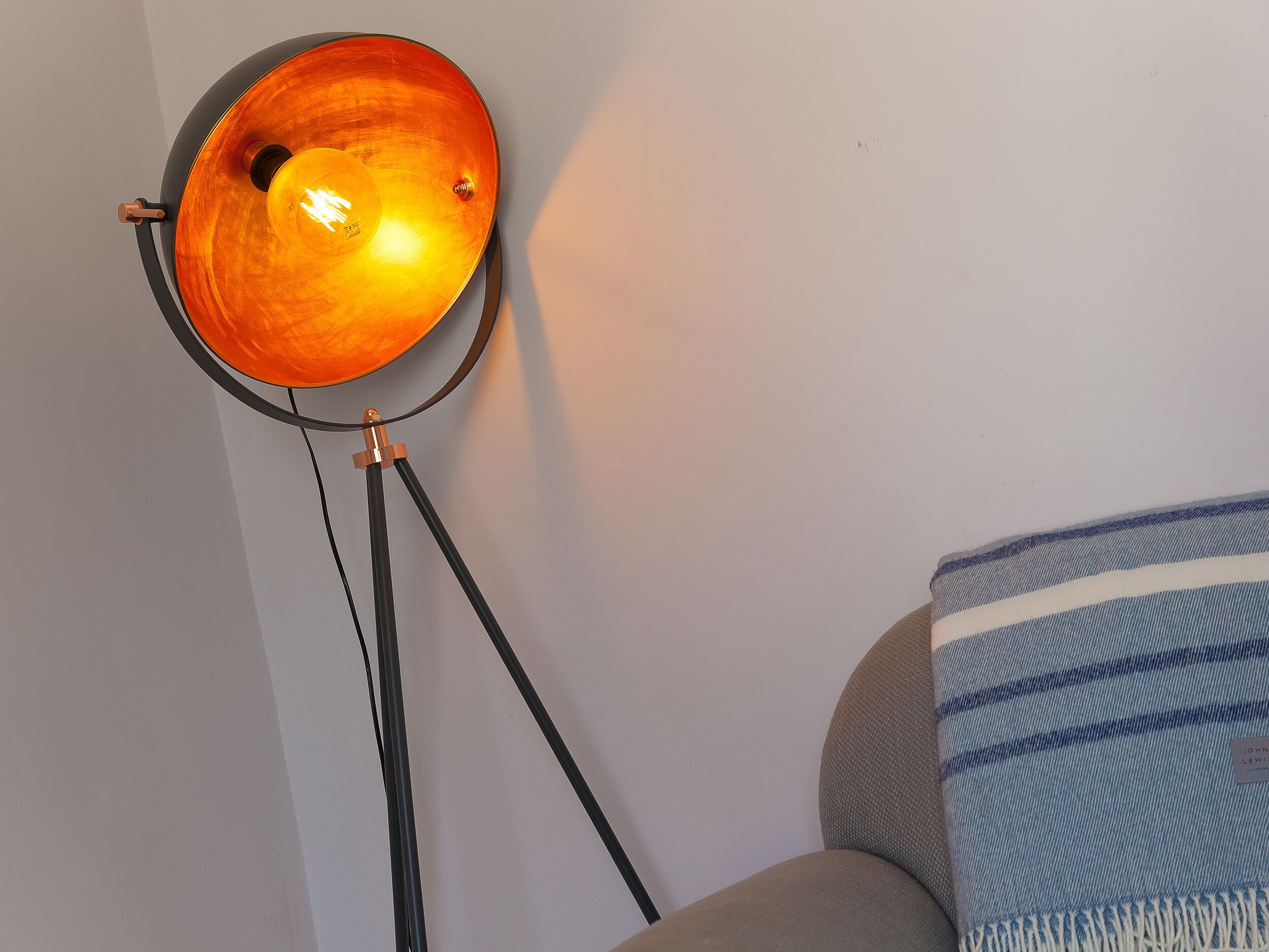 Eine stehende Lampe mit rundem, orangefarbenen Lampenschirm und schwarzem Sockel.