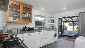 A modern kitchen with white cabinets, a built-in washing machine, a microwave, and a dining area with a view.