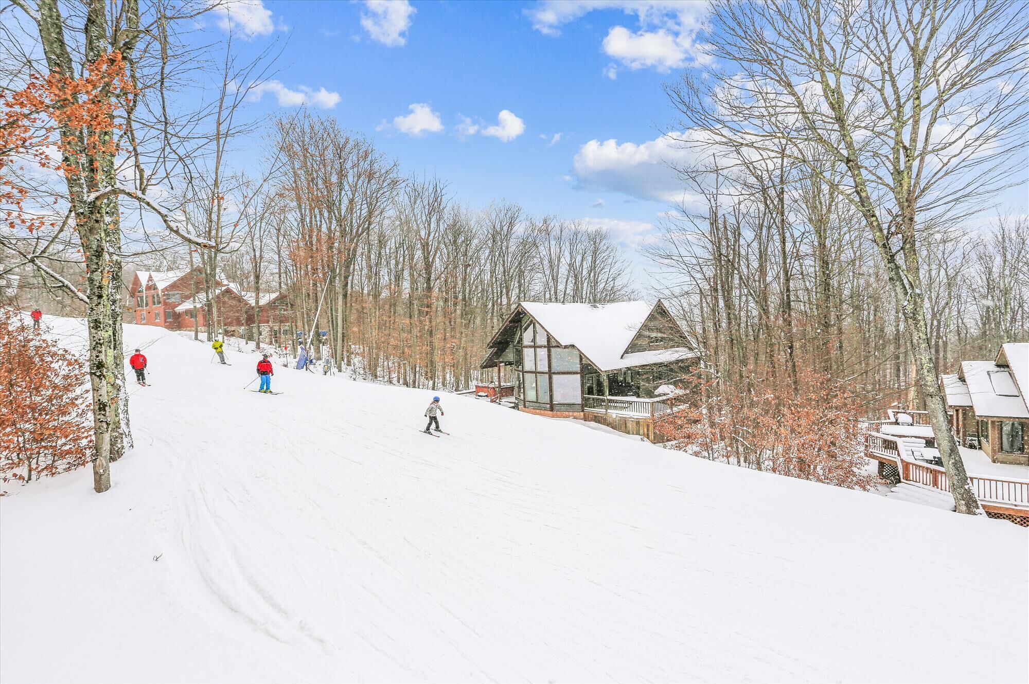 A snow-covered ski slope with a lodge featuring large windows and a wooden exterior.