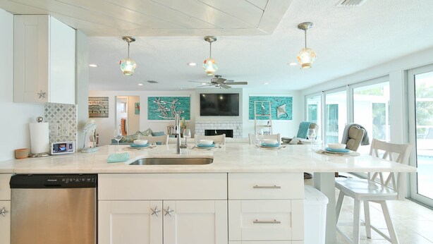 A modern kitchen with a central island, white cabinetry, and pendant lighting. - All Docked Out-Bring Your Own Boat! Private Heated Pool, Free WiFi 3 Mins to AMI (Bradenton)