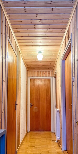 Ein schmaler Korridor mit Holzwänden und einer Holztür am Ende.