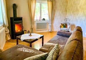 A cozy living room with a wood-burning stove, a sofa, a table, and a chair.