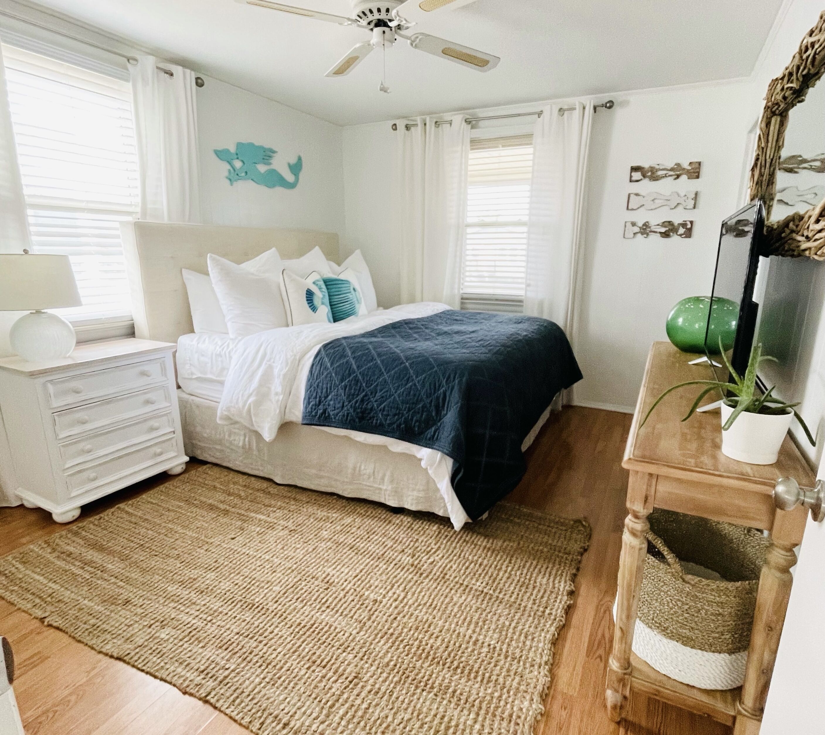 A bedroom with a bed, nightstand, dresser, and a ceiling fan.