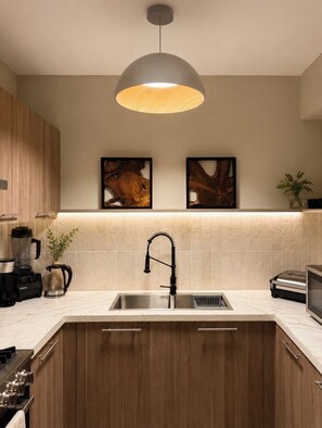 Een moderne keuken met een centraal eiland, een inbouwspoelbak, een zwarte kraan en een hanglamp erboven.