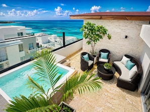 A rooftop pool area with a view of the ocean, wicker furniture, and a potted plant. - Mar Mary Ocean View (Boca Chica)