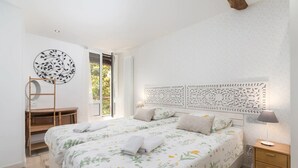 A bedroom with a large bed, a wooden nightstand, a desk with a mirror, and a decorative headboard. - Sarriegi | The Rentals Collection (San Sebastián)