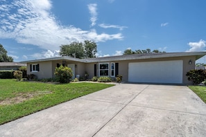 A single-story house with a garage, a front lawn, and a clear sky. - Cottage w/lanai and garage, 4 mi. Siesta Key (Sarasota)