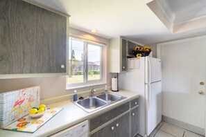 Eine Küche mit einem Doppelwaschbecken, einem Kühlschrank und einem Fenster mit Blick nach draußen.