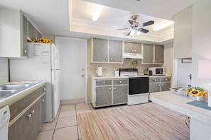 A modern kitchen with grey cabinets, a built-in oven, microwave, and a ceiling fan. - Cottage w/lanai and garage, 4 mi. Siesta Key (Sarasota)