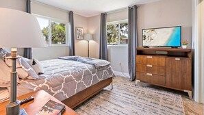 A bedroom with a bed, a TV, a dresser, and a window with curtains. - Sarasota Getaway Near Siesta Key, Screened Lanai + Garage, Pet Friendly (Sarasota)