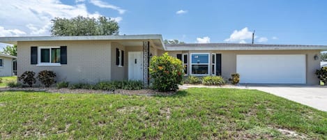 A single-story house with a garage, a well-maintained lawn, and a clear sky.