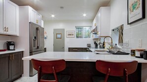 A modern kitchen with white cabinets, stainless steel appliances, and a central island with bar stools. - Fancy 1-BR in Central Location (Washington)