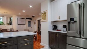 A modern kitchen with dark cabinetry, a stainless steel refrigerator, and a marble countertop. - Fancy 1-BR in Central Location (Washington)