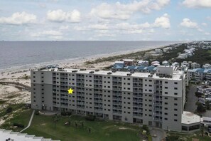 A multi-story hotel with a flat roof, located near a beach.