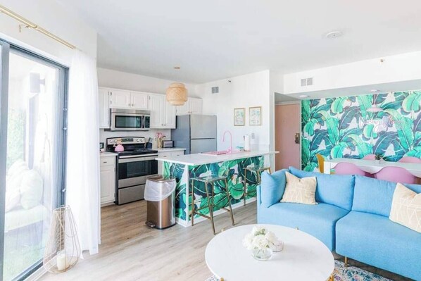 A modern kitchen with white cabinets, stainless steel appliances, and a central island with a pink sink.