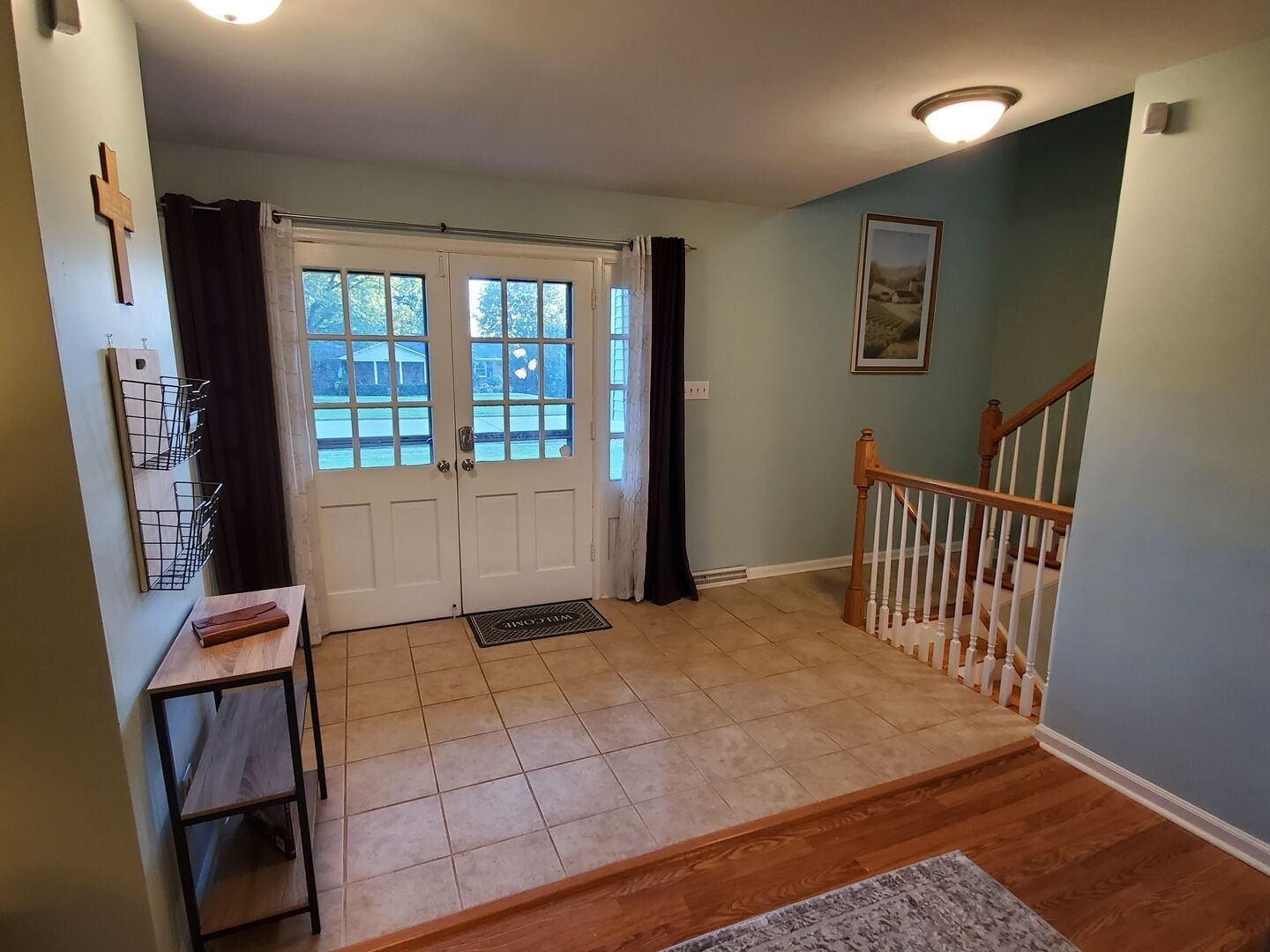 A hallway with a double door, a staircase, and a wall-mounted light fixture.