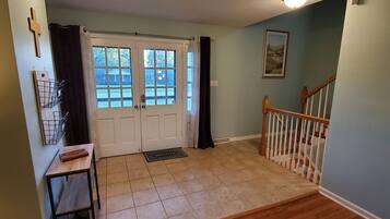 A hallway with a double door, a staircase, and a wall-mounted light fixture.
