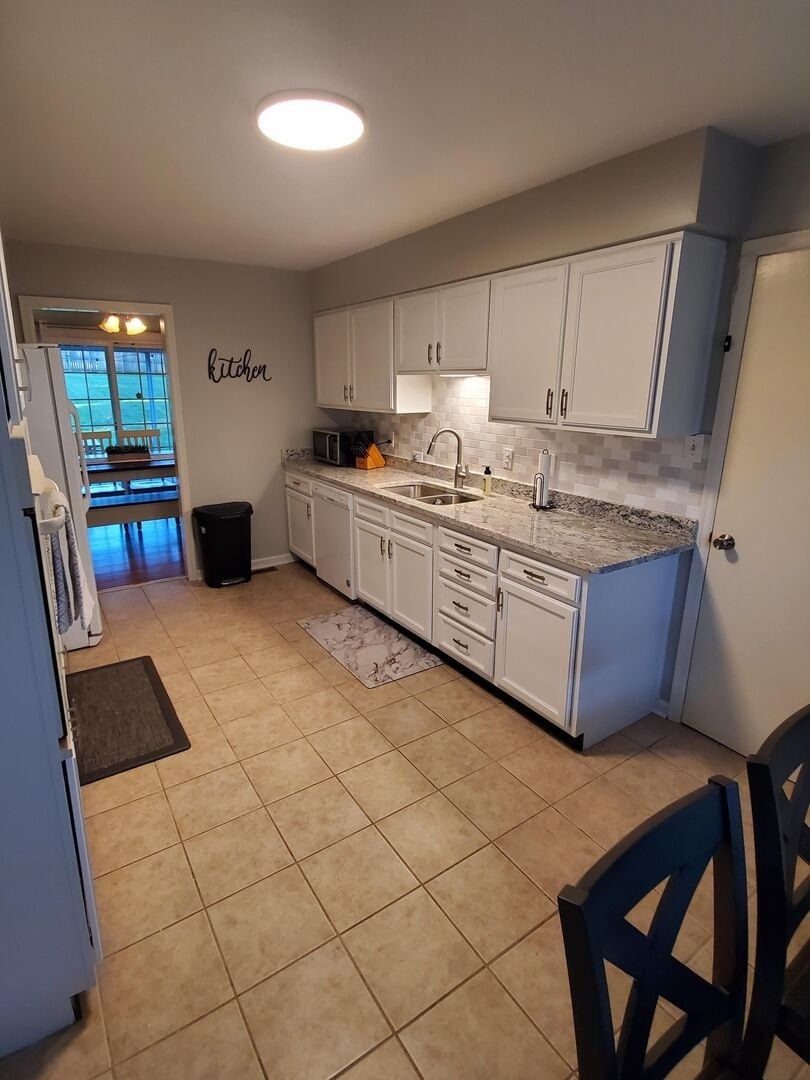 A kitchen with white cabinets, a granite countertop, and a microwave.