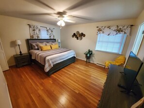 A bedroom with a bed, a ceiling fan, a window with blinds, a small plant, and a desk with a computer. - Andrea Abode 5 Bedroom Home by RedAwning (Lexington)