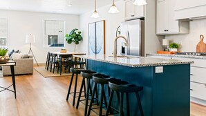 Una cocina moderna con una isla central, taburetes de bar e iluminación colgante.