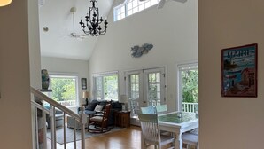Un amplio espacio de sala con una mesa de comedor, sillas y una escalera que sube a otro nivel.