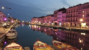 A canal with boats docked, buildings along the water, and street lamps.