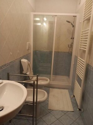 A bathroom with a shower, toilet, and sink. - Near the center (Lucca)