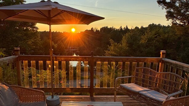 A wooden deck with wicker furniture, a table, and an umbrella.