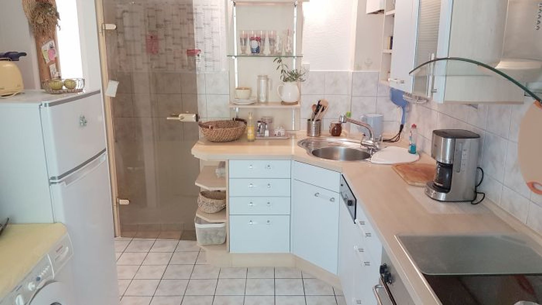 Eine kleine Küche mit Kühlschrank, Spüle und Kaffeemaschine.