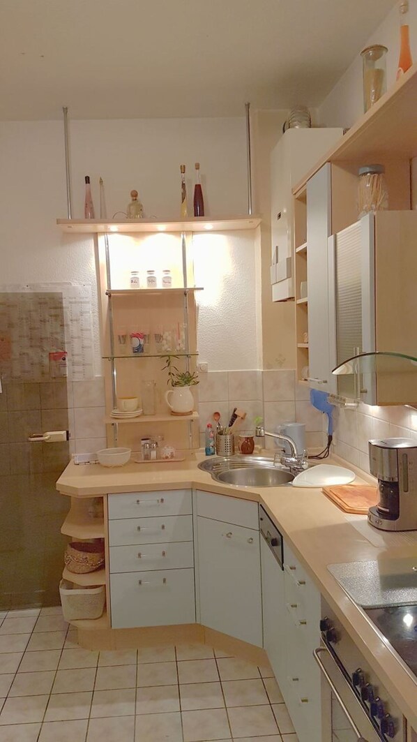 Cocina compacta con pileta, cafetera y microondas. Hay placares y una mesada con diversos objetos.
