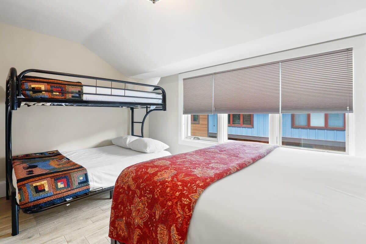 A bunk bed room with a window and a view of buildings outside.