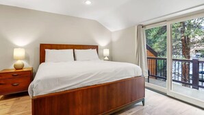 Una camera da letto con un letto di legno, due comodini con lampade e un'ampia finestra con balcone.