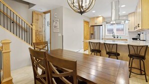 Una cucina moderna con isola centrale, sedie in legno e una scala con ringhiere in legno.